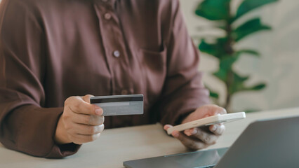 A woman is holding a credit card and a cell phone