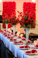 Formal wedding reception with red flowers.
