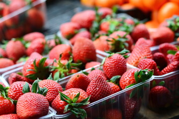 a collection of fresh strawberries are gathered in baskets on a sale table at a farmer's market.