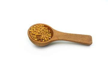 Fenugreek seeds in a wooden spoon isolated on white background
