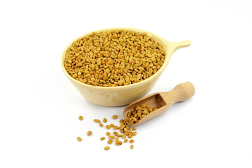Fenugreek seeds in a bowl with spoon  isolated on white background