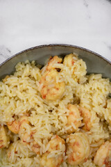 Seafood. Top view of a bowl with shrimps and rice with saffron on the white marble table.