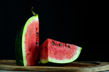 Fresh watermelon on a black background, cut into pieces. Daylight, selective focus with copy space