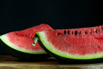 Large pieces of ripe watermelon on a wooden table with a black background.Natural light