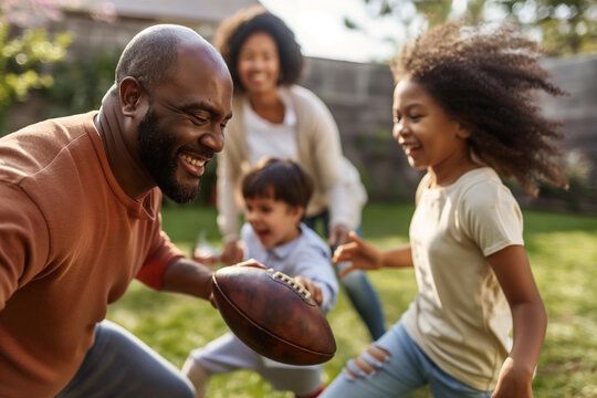 A joyful family playing football outside, father and children laughing. Concept for family time and outdoor fun