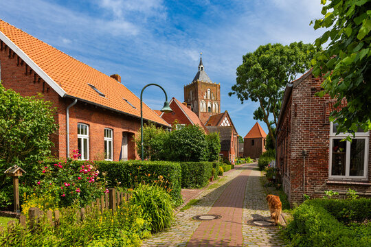 Dorfstra&szlig;e in Pilsum mit Blick auf die Kreuzkirche St. Stephanus; Ostfriesland; Deutschland