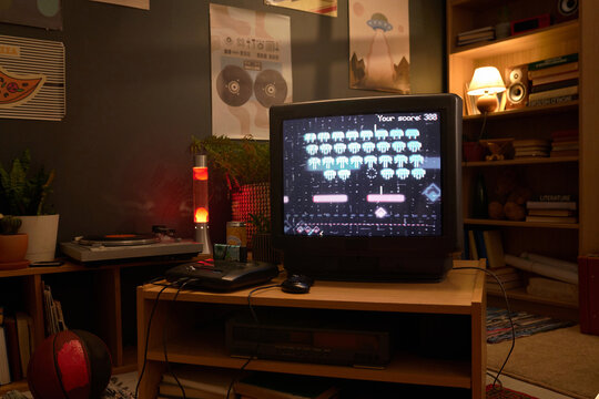 Close-up shot focusing on retro TV gaming setup with eighties eight bit arcade video gamein cozy living room, highlighting vintage technology and nostalgic decor elements