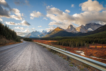Fototapeta premium Gravel road leading through a scenic mountain valley in autumn