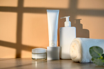 White plastic container with a dispenser and face cream and a white towel.
