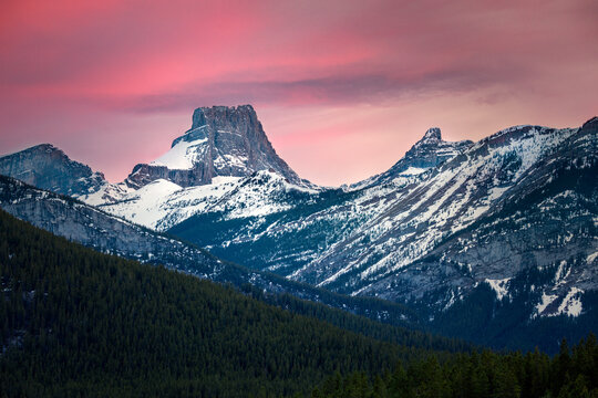 Dramatic pink sunset illuminating snow capped mountain peaks