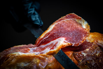 Chef cutting dry-cured spanish ham Jamon.