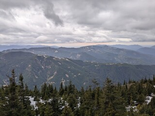 Distant mountains under cloudy sky with wooded hills in the foreground