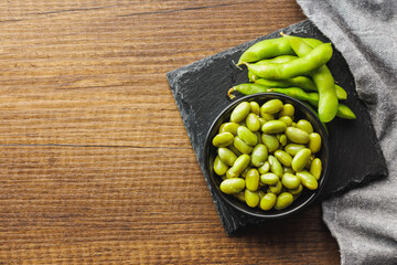 Edamame soy beans in bowl on wooden table. Top view.