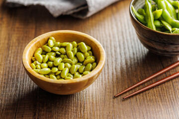 Edamame soy beans in bowl on wooden table.