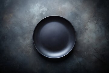 Empty black plate on a dark, textured background, perfect for minimalist food presentations or kitchen-themed photography projects.