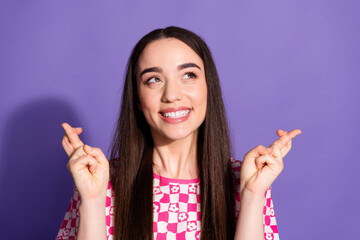 Photo of pretty young woman crossed fingers look empty space wear checkered t-shirt isolated on...