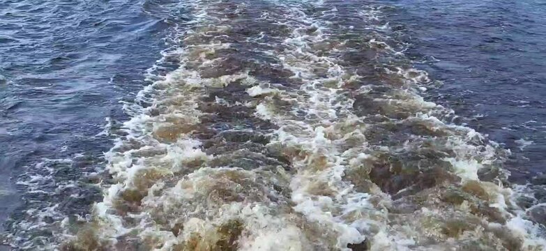 Swirling blue waves astern of a moving ship