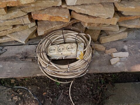 There is an electrical extension cord with many outlets near a mountain of sandstone rocks