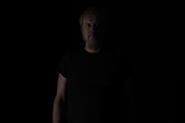 dark portrait of a bearded old man on a black background