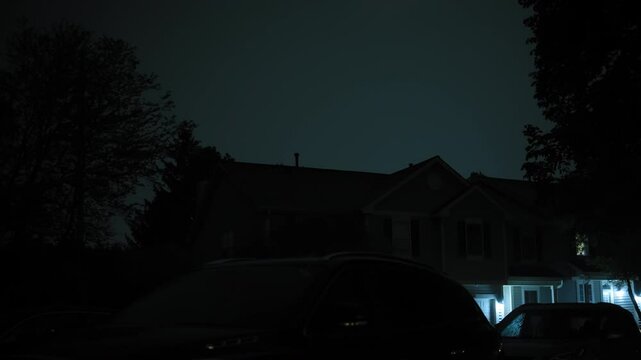 Lightning flashing above the house in the suburbs. Wide view of Night time storm