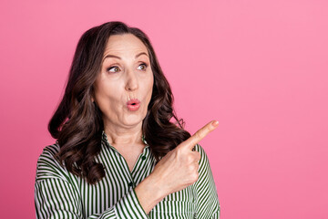 Photo of nice aged lady look direct finger empty space wear striped shirt isolated on pink color background