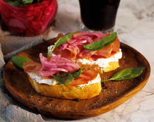 Rustic Toasted Sandwiches with Ricotta, Balik, and Marinated Onion on Wooden Board. High quality photo