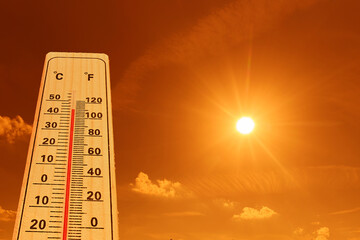 Hot whether concept. A thermometer showing high temperatures under a bright and intense sun.