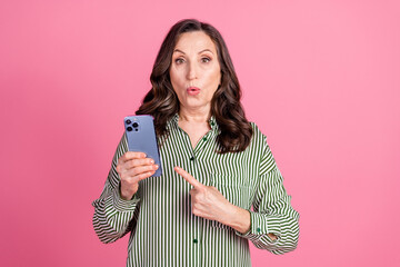 Photo of nice aged woman point finger smart phone wear striped shirt isolated on pink color background