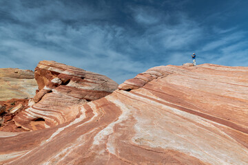 A person is standing on a rocky hillside with a beautiful view of the sky
