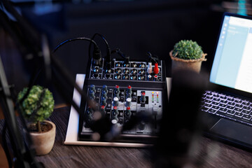 Professional podcasting setup with laptop, modern audio mixer and numerous buttons for dynamic...