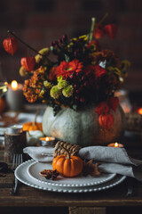 Fall composition. Orange pumpkins, flowers and candles on wooden table. Family elegant Thanksgiving or halloween dinner. Cozy autumn concept, simple handmade decoration, countryside style, wine