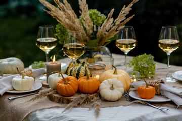 Autumn cozy mood table composition for family thanksgiving dinner with wine, pumpkins, candles on wooden tray. Fall mood, warm plaid. Hygge home decor, interior seasonal design