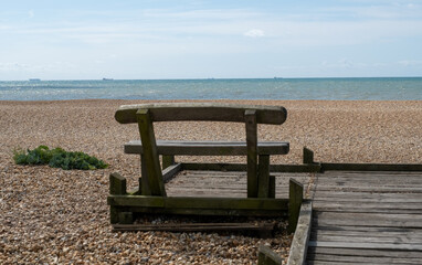Wooden bench looking out to sea on the beach in Dungeness on the Kent coast