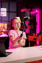 Talented young entertainer doing livestream using cellphone attached to selfie stick. Upbeat youngster does live broadcast using phone camera to talk with online subscribers