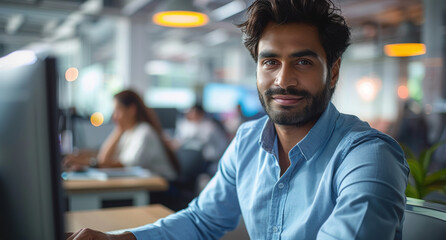 Portrait of a South Asian Financial Securities Trader Working on Desktop Computer in a Modern Office. Handsome Indian Accountant Bookkeeping Financial Affairs of a Business Venture