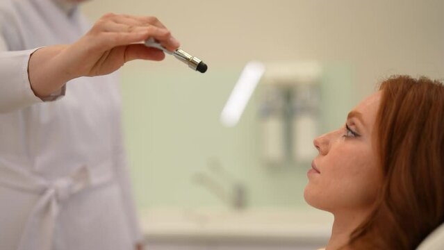 Close-up of unrecognizable doctor neurologist examining young female patient reflexes during appointment. Closeup of neurological hammer to test reflexes in medical office. Shooting in slow motion.