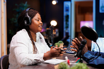 Woman radio show presenter having conversation with person, recording with audio equipment for...