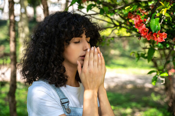 Dark-haired young woman sneezing and feeling unwell, having allergy symptoms
