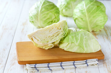 Whole and quarter green cabbage on a wooden table,