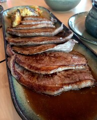 Detalhe de carne de vaca (picanha) cozinhada em travessa de loiça em restaurante.