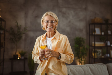 Portrait of mature senior woman sit and hold glass of wine