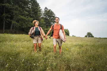 Fototapeta premium Boyfriend and girlfriend walk around forest with camp equipment
