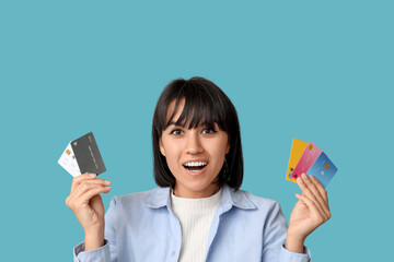 Beautiful young woman with many credit cards on blue background