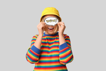 Surprised adult woman holding speech bubble with word WOW on white background