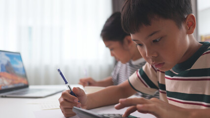 Asian elementary school children studying mathematics in class intently.