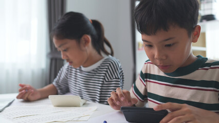 Asian elementary school children studying mathematics in class intently.