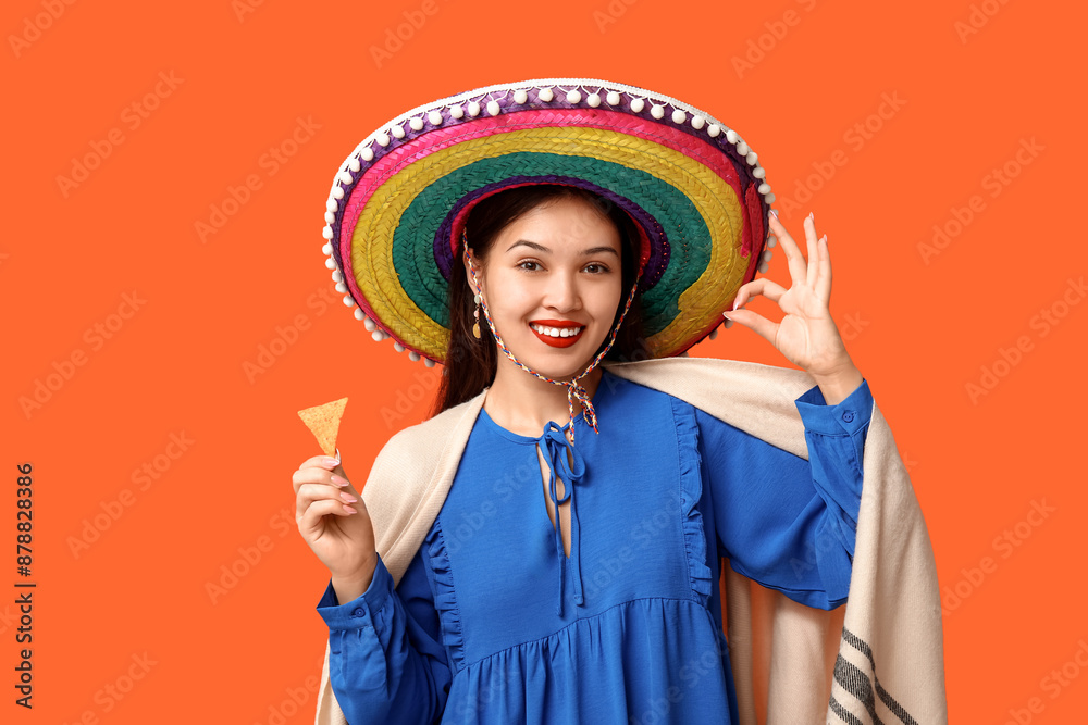 Sticker Portrait of young woman with sombrero and tortilla chip showing OK on orange background. National Tortilla Chip Day celebration