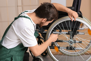 Obraz premium Male worker with wrench repairing wheelchair in room