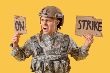 Protesting male soldier holding placard with text ON STRIKE against yellow background
