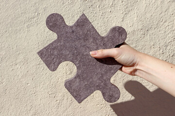 Eine Frau hält ein großes Puzzle Teil aus Stein in der Hand